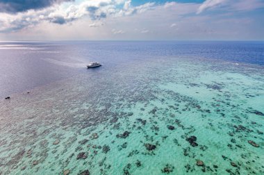 Sudan Kızıldeniz 'de canlı bir mercan resifinin yanında bir dalış botu duruyor, Sanganeb Deniz Feneri' nden görüldüğü gibi. Su altı keşiflerinin sakin güzelliği.