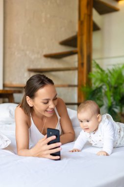 Babasıyla çevrimiçi görüntülü konuşma sırasında yeni doğmuş kızıyla birlikte genç bir anne. Bir kadın kızlarını babasına gösterir, gülümser ve kocasıyla iletişim kurar..