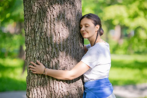 A 35-year-old woman hugs a tree. The concept of love for nature and energy exchange.