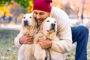 Mutlu orta yaşlı adam köpeğini kucaklıyor, golden retriever. Dostluk, sevgi ve evcil hayvan bakımı. Yakın çekim görünümü.