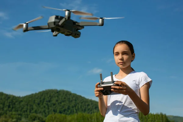 A teenage girl controls a drone on a sunny summer day outdoor.