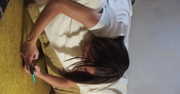 Asyalı Genç Kız Akıllı Telefonuyla Battaniyeyi Örterek Yatakta Yatıyor Akıllı — Stok video