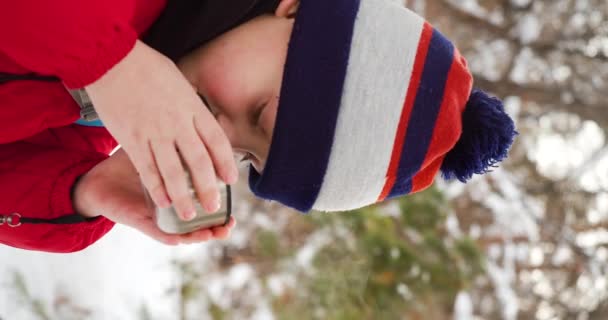 冬の雪の森をハイキングしながら暖かいお茶を飲む9歳の少年のビデオ スローモーション4K映像 — ストック動画