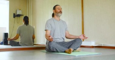 Meditasyon yapan orta yaşlı bir adamın 4K görüntüsü. Akıl sağlığı konsepti. Dolly vurdu..