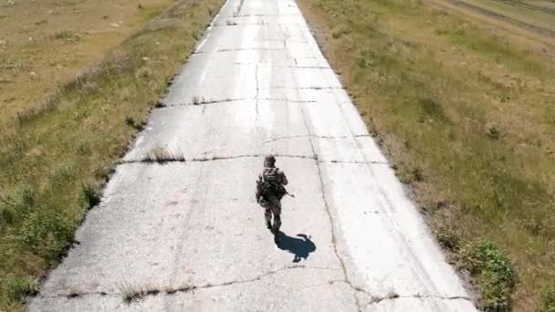 一人の疲れた兵士が古いコンクリートの道を歩いている 空中4K映像 バックビュー — ストック動画