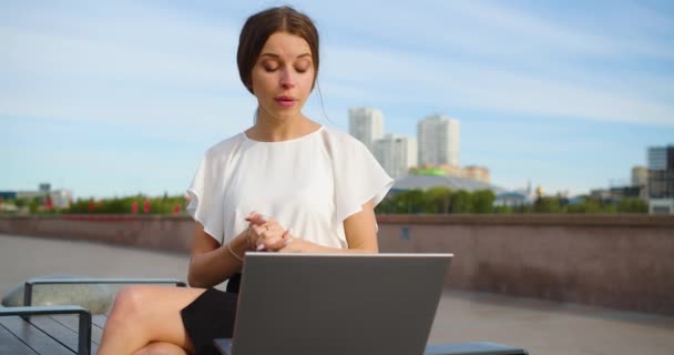 年轻的女商人在一个网上视频通话 她在城市景观的背景下 通过笔记本电脑通过视频通信进行交流 4K镜头 — 图库视频影像