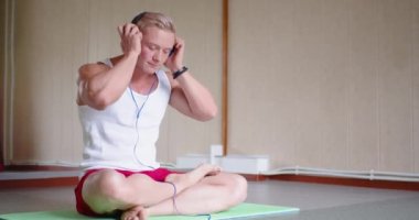 Spor salonundaki antrenmandan sonra rahatlama. Vücut geliştirici, akıllı telefonuyla rahatlatıcı müziği açar ve meditasyon yapar. 4k görüntü.