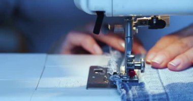 Dikiş makinesinde çalışan bir kadının ellerine yakından bakın. 4k 'lık yakın çekim..