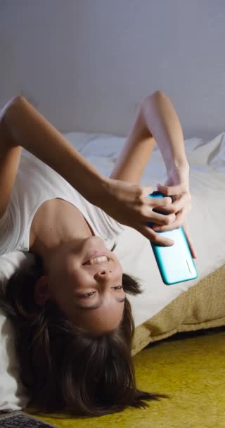 Fps Imágenes Verticales Una Adolescente Encuentra Cama Con Teléfono Inteligente — Vídeo de stock