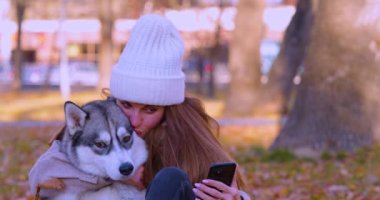 Genç bir kadın ve köpeği Husky 'nin parkta yürürken oynadıkları video. Dostluk ve evcil hayvan bakımı. Yavaş çekim 4k görüntü.