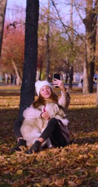 İnternetteki video görüşmesi sırasında boğasını kucaklayan genç bir kadın. Sosyal ağlardaki modern trendler ve hayvanlara duyulan sevgi. Yavaş çekim 4k görüntü.