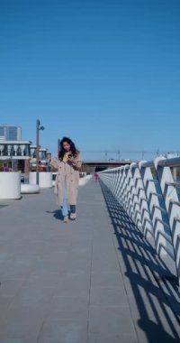 Harika haberlerim var. Elinde akıllı telefon olan Asyalı bir kadın mutluluktan zıplıyor. İyi haberler aldı, işe alındı. Şehir manzarası. 4k görüntü.