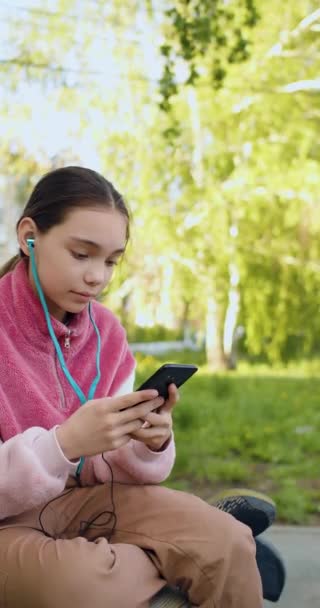 10岁的女孩带着智能手机和朋友们在户外聊天 垂直4K段 — 图库视频影像