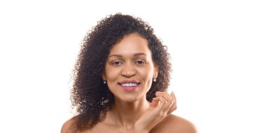 30 yaşında, beyaz arka planda soyutlanmış, tenine dokunan Afro-Amerikalı bir kadın. Format fotoğrafı 2x1. Kameraya bakıyor ve gülümsüyor. Biçim fotoğrafı 2x1.