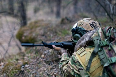 Ordu istilası. Bir asker pusudan düşmana nişan alır. Modern savaş ve özel kuvvetler kavramı. Kesilen resim.