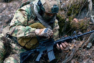 Çarpışma sırasında paralı asker silahı topraktan ve pislikten temizliyor. Düşmana saldırmaya hazırlanıyor. Yakın çekim görüntüsü. Seçici odak.