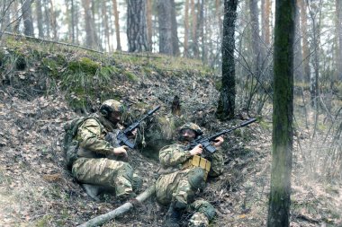 Ormandaki özel bir operasyon sırasında pusuda bekleyen iki paralı asker. Saldırmadan önce düşmandan saklanıyorlar. Kolaj - iki pozda bir model.