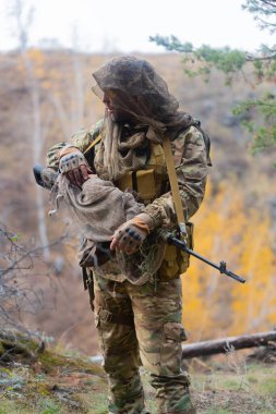 Düşman hattının arkasındaki sabotaj sırasında paralı bir askeri keskin nişancının dikey fotoğrafı. Modern savaş görevleri ve düşman hatlarının gerisindeki provokasyonlar..