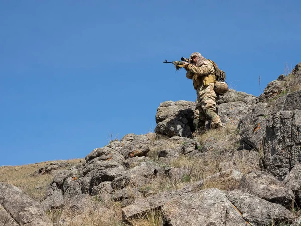 Special forces professional sniper aiming at the enemy in the mountains. Ambush in the mountains. The concept of modern military operations and a special operation on enemy territory.