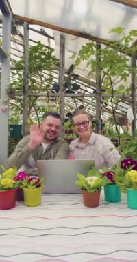 Bir çift online video görüşmesi sırasında - akrabalarına ya da arkadaşlarına küçük işletmelerinden bahsederler - ang ev bitkileri mağazası bahçıvanlığı. Dikey 4k görüntü.