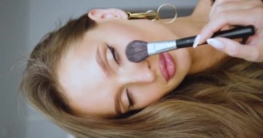 Kafkasyalı güzel bir kadının allık sürerek makyaj yaptığı dikey 4K video..