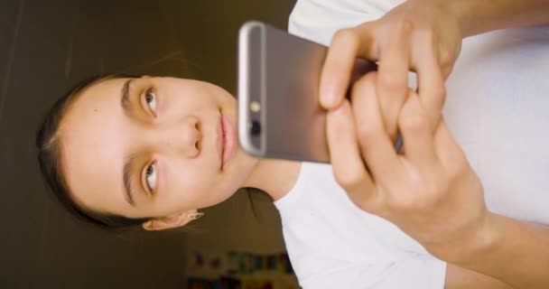 スマートフォンを持つ10歳の少女 彼女は積極的にオンラインチャットで友人と通信します 4K映像 — ストック動画