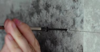 Yakın plan - erkek elleri duvara vida vidalarken tornavidayla resim asıyor. 60 fps 4k görüntü.