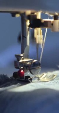 Dikiş makinesi iğnesinin hızlı hareketi. Dikiş makinesi mekanizmasının makro görüntüsü. Dikiş makinesine kot kumaşı dikiyorum. 4k 'lık yakın çekim..