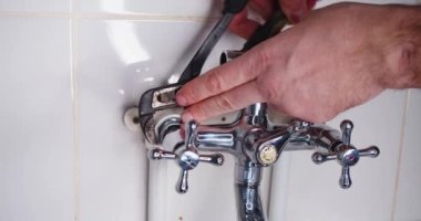 Plumber tightens nut with adjustable wrench during faucet installation. Male hands close-up. Slow motion 4k footage.