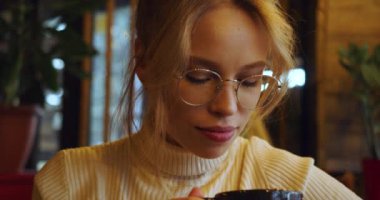 Close-up video of a young woman in glasses enjoying drinking tea. Slow motion 4k footage.