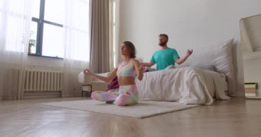 Orta yaşlı bir çiftin evde meditasyon yaparken 4K görüntüsü. Yoga, pilates ve sağlık hizmeti konsepti.