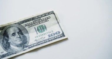 American banknotes of different denominations fall on a white table. Counting money - top view. Slow motion 4k video.