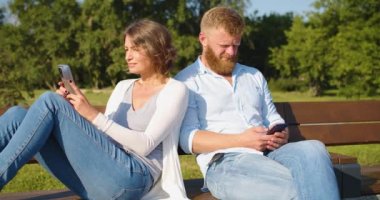 Psychology of family relationships - a middle-aged couple sits buried in smartphones and ignores each other. Digital addiction concept.