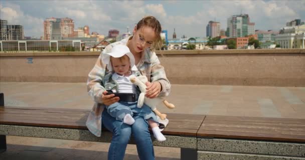 彼女の娘と若い母親は スマートフォンのオンラインアプリケーションを通じて子供のための教育ビデオを見ています 4K映像 — ストック動画