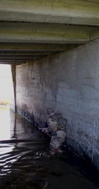 A mercenary soldier sneaks out of a flooded enemy bunker blocked by the enemy. The concept of modern warfare in underground structures. 4k footage.
