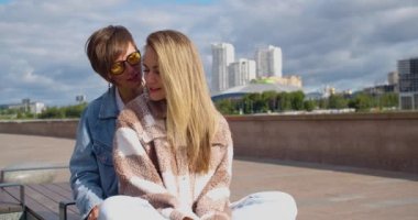 Lesbian couple sit on the embankment and enjoy each other. Love and relationships concept. Beautiful romantic moment between two female lovers. Vertical 4k footage.