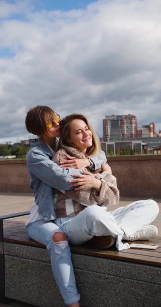 2人のレズビアン女性が堤防の上に座り お互いを楽しむ 愛と関係の概念 2人の女性愛好家の間で美しいロマンチックな瞬間 縦4K映像 — ストック動画