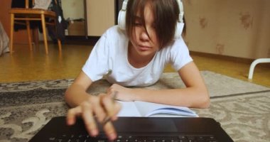 Online education concept - video of a schoolgirl doing homework online in front of a laptop monitor. Slow motion 4k footage.