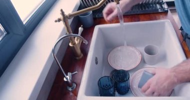 Close-up 60 fps 4k video of a male hands wash dishes. View from the top.