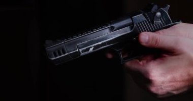 Close-up footage of a mens hands with a gun in the dark. Slow motion 4k video.
