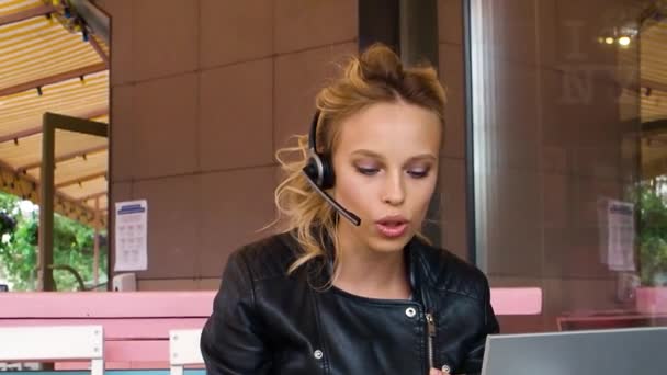 真剣な若い女性がオンラインビデオ通話を開始します 彼女はラップトップモニターの前でオンラインビデオ通話中に歩道カフェに座っています Fhd映像 — ストック動画