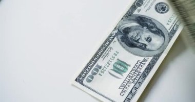 Top view of a US banknotes of different denominations fall on a white table. Counting money - top view. Slow motion 4k video.