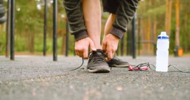 Close-up - a man tying his shoelaces on sneakers before an outdoor workout.