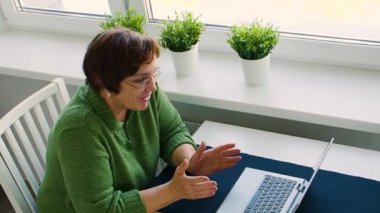 Footage of a senior woman during a conversation via online video call.