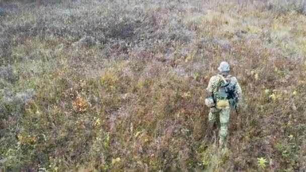 ドローンカメラは 秋のシーズン中に草の上を歩く一人の兵士に続く — ストック動画