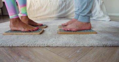 Karışık ırk çiftleri Sadhus tahtalarında karşı karşıya keskin tırnaklarla duruyorlar. Yoga pratiği. 4k görüntü.