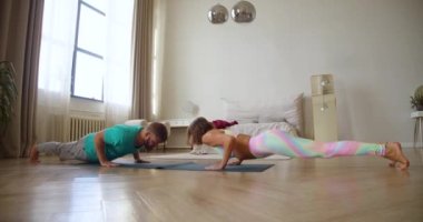 Middle aged couple practicing yoga at home. They do upward dog exercise. 4K footage.