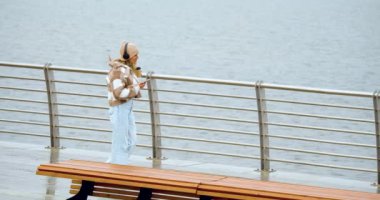 Young woman dancing while walking along the embankment - she is listening to music on headphones using an online smartphone application. Dolly shot - 4k footage.