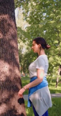 A 35-year-old woman hugs a tree. The concept of love for nature and energy exchange. Vertical 4k footage.