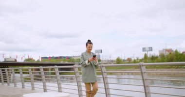 Great news - Caucasian woman with a smartphone in her hand is jumping with happiness. Urban scene outdoor. Slow motion 4k footage.